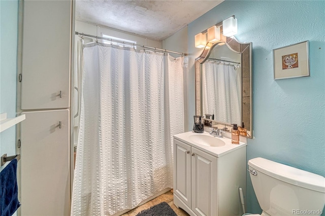 bathroom featuring vanity, curtained shower, a textured ceiling, and toilet