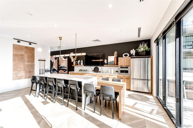 kitchen featuring a center island with sink, a breakfast bar, hanging light fixtures, and appliances with stainless steel finishes