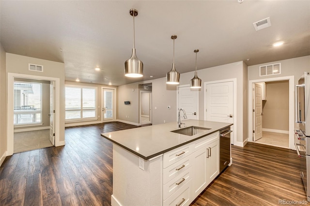 kitchen with dark hardwood / wood-style flooring, a kitchen island with sink, sink, and decorative light fixtures