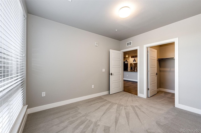 unfurnished bedroom featuring light colored carpet, a spacious closet, and a closet