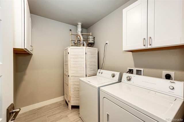 laundry area featuring separate washer and dryer, cabinets, and light hardwood / wood-style floors