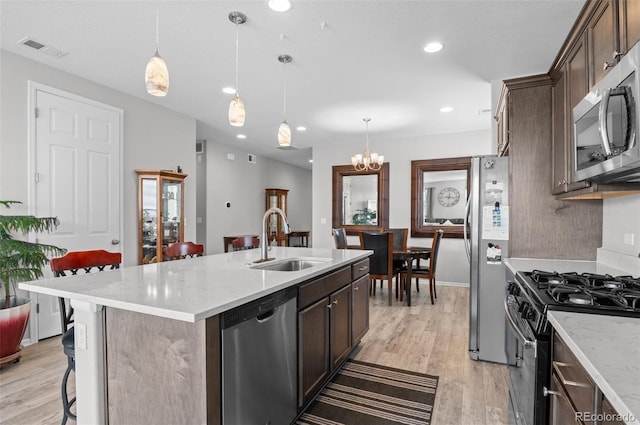 9883 Truckee St, Commerce City, CO 80022 - kitchen with visible vents, a sink, light wood-type flooring, a kitchen island with sink, and stainless steel appliances