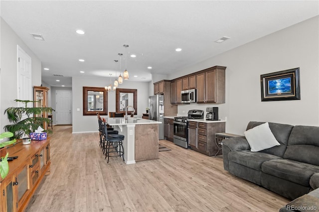 9883 Truckee St, Commerce City, CO 80022 - kitchen featuring visible vents, open floor plan, appliances with stainless steel finishes, a kitchen breakfast bar, and light wood-style flooring