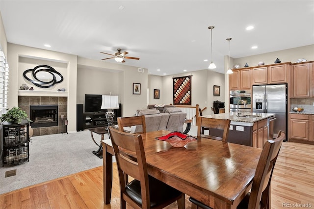 8582 E 148th Ln, Thornton, CO 80602 - dining room featuring light wood-type flooring, ceiling fan, a tile fireplace, and recessed lighting