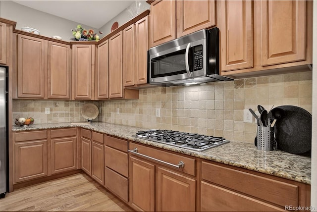 8582 E 148th Ln, Thornton, CO 80602 - kitchen featuring appliances with stainless steel finishes, light wood-type flooring, light stone countertops, and tasteful backsplash