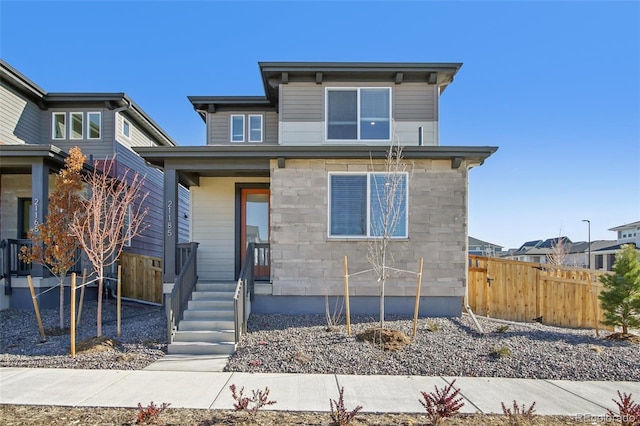 view of front of property featuring stone siding and fence