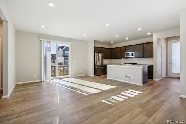 kitchen with light wood finished floors, visible vents, appliances with stainless steel finishes, open floor plan, and dark brown cabinets