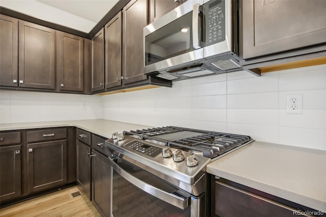 kitchen featuring appliances with stainless steel finishes, light countertops, dark brown cabinetry, and backsplash