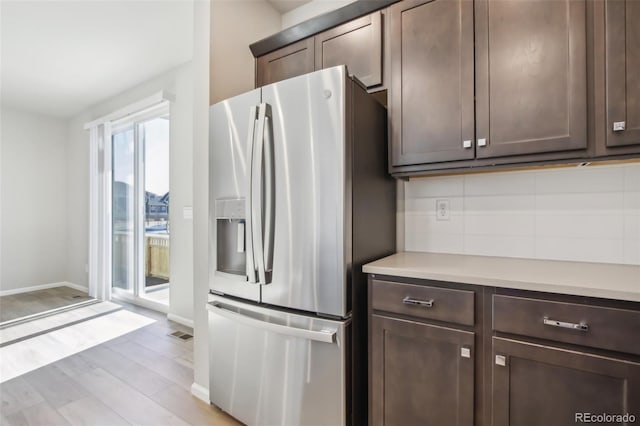 kitchen featuring light wood-type flooring, dark brown cabinetry, stainless steel fridge, and light countertops