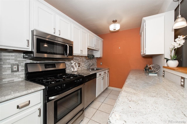 kitchen featuring decorative backsplash, appliances with stainless steel finishes, sink, white cabinetry, and light tile patterned flooring