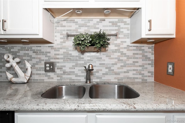 kitchen featuring white cabinets, decorative backsplash, light stone countertops, and sink