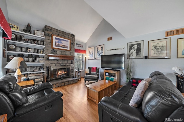 living room with a fireplace, vaulted ceiling, and light hardwood / wood-style flooring