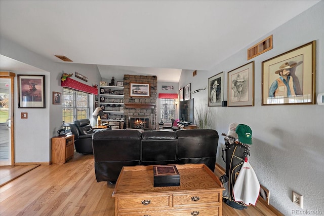 living room with light wood-type flooring and a stone fireplace