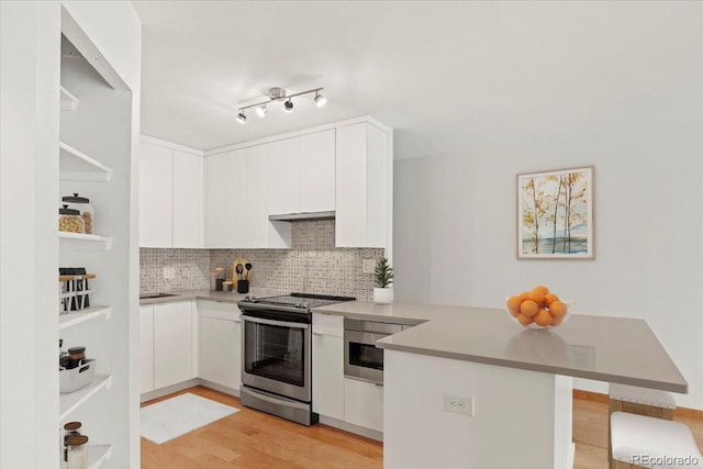 550 E 12th Ave Unit 209, Denver, CO 80203 - kitchen with stainless steel electric range, a peninsula, light wood-style floors, decorative backsplash, and under cabinet range hood