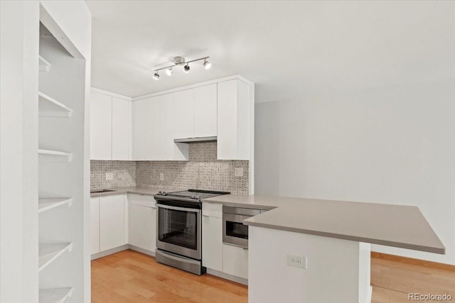 550 E 12th Ave Unit 209, Denver, CO 80203 - kitchen with electric range, a peninsula, light wood finished floors, white cabinetry, and tasteful backsplash