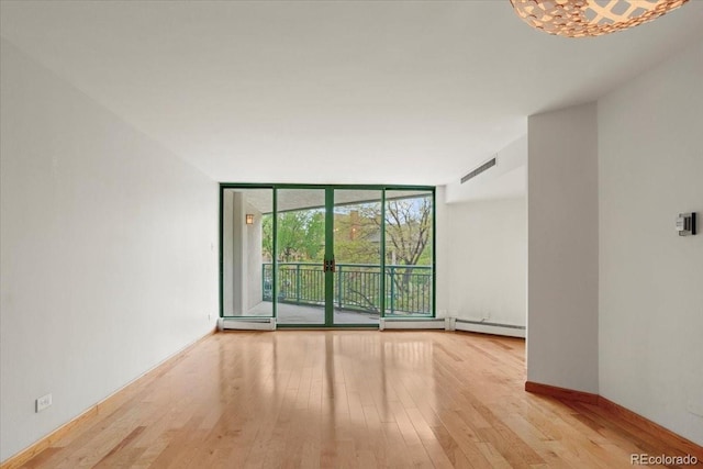 550 E 12th Ave Unit 209, Denver, CO 80203 - spare room featuring a wall of windows, a baseboard heating unit, wood finished floors, and baseboards