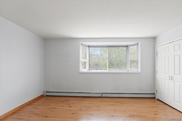 550 E 12th Ave Unit 209, Denver, CO 80203 - unfurnished bedroom featuring light wood-style floors, a baseboard radiator, and baseboards