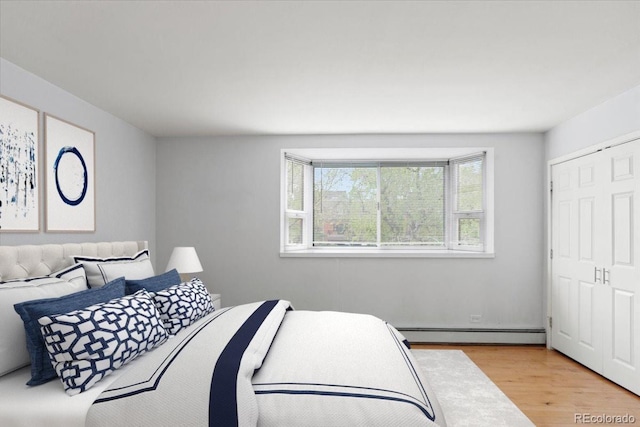 550 E 12th Ave Unit 209, Denver, CO 80203 - bedroom with a baseboard heating unit and light wood-style flooring