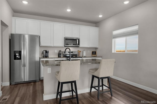 kitchen with a center island with sink, dark hardwood / wood-style floors, white cabinetry, and stainless steel appliances