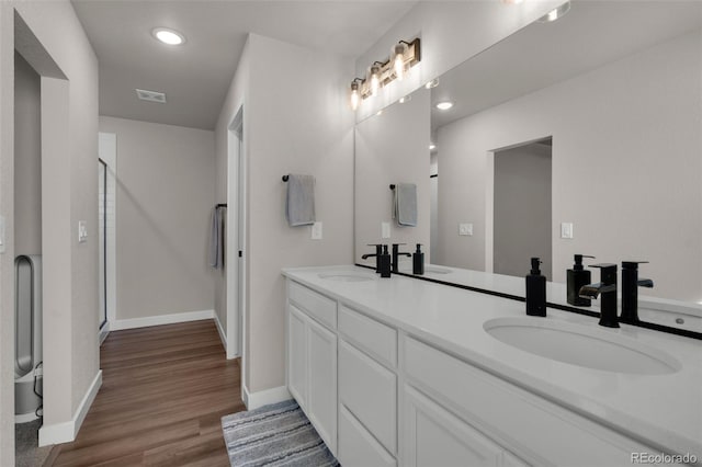 bathroom with hardwood / wood-style floors, vanity, and an enclosed shower