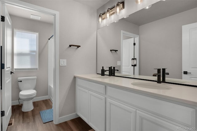 full bathroom with wood-type flooring, vanity, shower / bath combination, and toilet