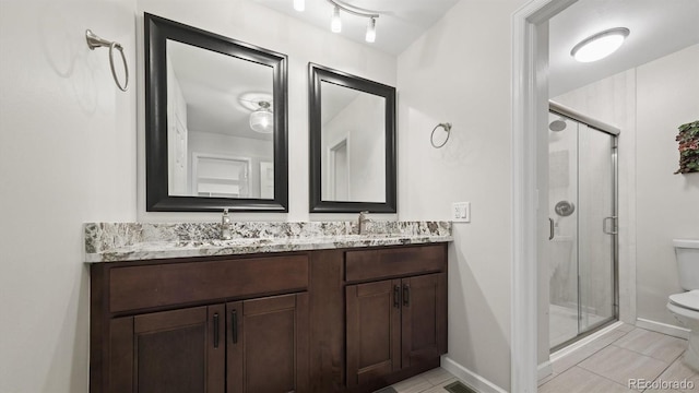 bathroom featuring toilet, tile patterned flooring, a shower with shower door, and vanity