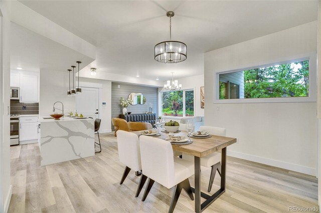 1304 Snowberry Unit 103, Louisville, CO 80027 - dining room with light wood-style flooring, baseboards, and a chandelier
