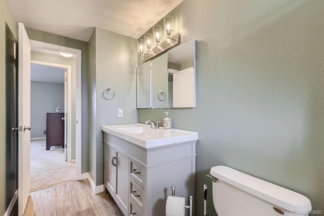 bathroom featuring vanity, wood-type flooring, a textured ceiling, and toilet