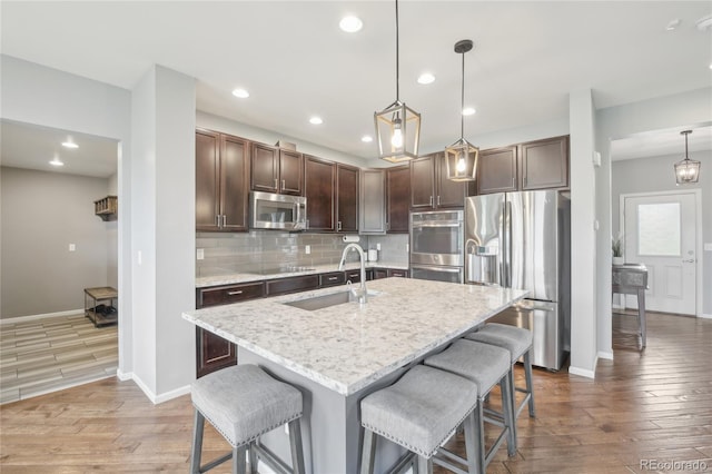 16226 W 94th Dr, Arvada, CO 80007 - kitchen with appliances with stainless steel finishes, a sink, wood finished floors, a breakfast bar, and backsplash