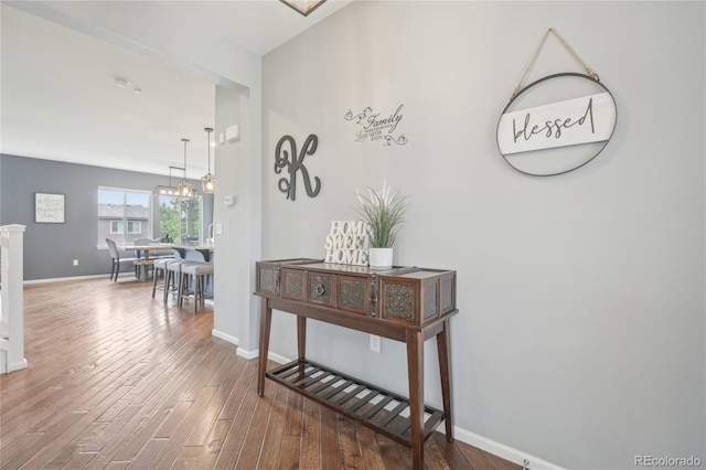 16226 W 94th Dr, Arvada, CO 80007 - hallway with wood finished floors, baseboards, and a chandelier