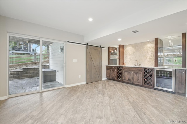 16226 W 94th Dr, Arvada, CO 80007 - unfurnished living room featuring beverage cooler, wet bar, a barn door, light wood-type flooring, and baseboards