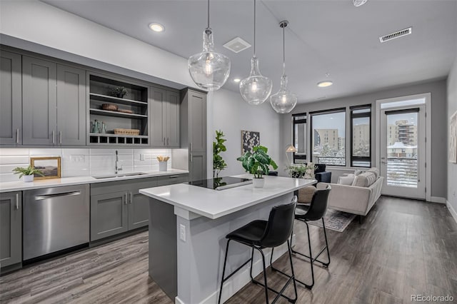 kitchen featuring a breakfast bar area, a kitchen island, gray cabinets, black electric stovetop, and dishwasher