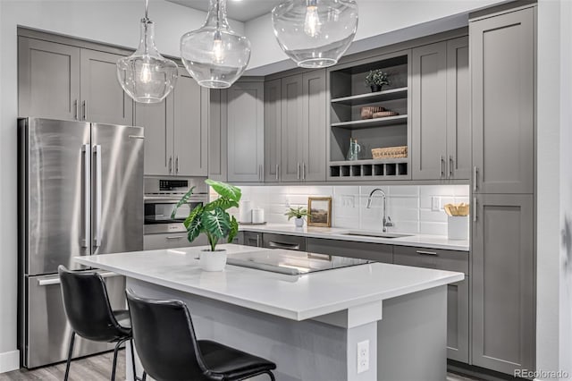 kitchen featuring stainless steel appliances, gray cabinets, sink, and a kitchen island