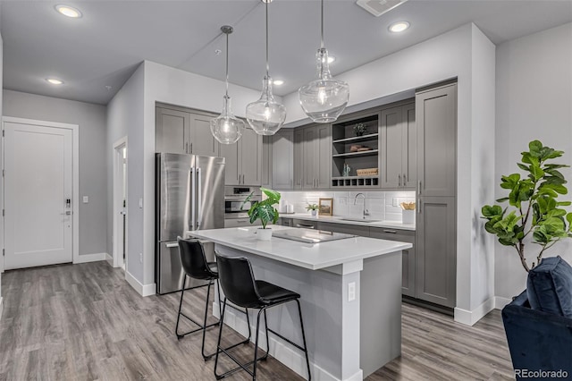 kitchen with gray cabinets, a kitchen island, pendant lighting, and appliances with stainless steel finishes