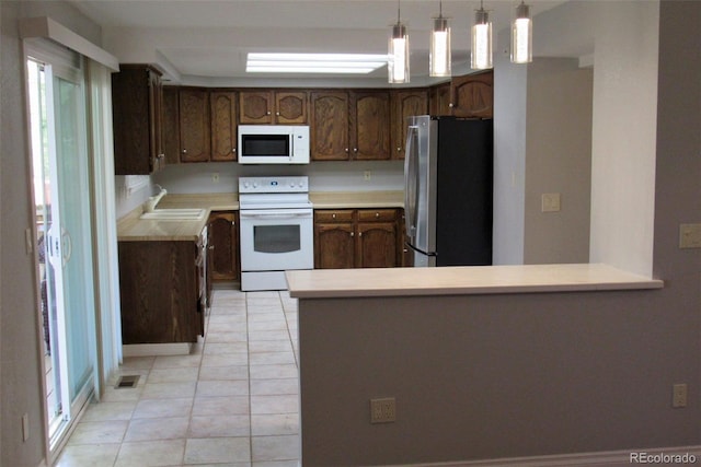 14503 E Wagon Trail Dr, Aurora, CO 80015 - kitchen featuring white appliances, a sink, light tile patterned floors, light countertops, and a peninsula