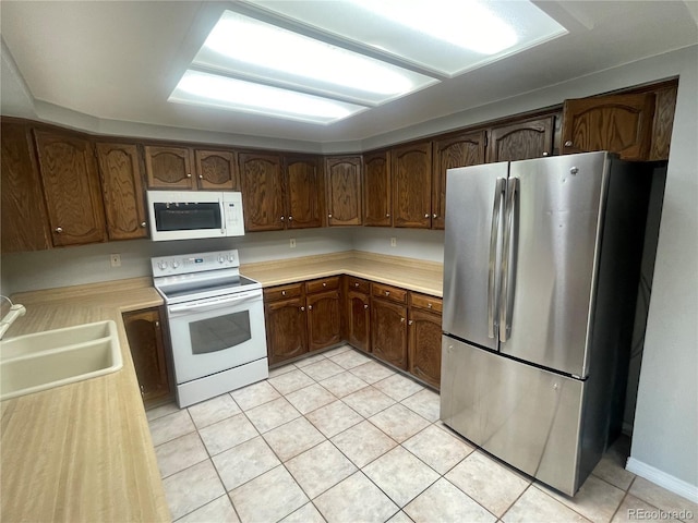 14503 E Wagon Trail Dr, Aurora, CO 80015 - kitchen featuring white appliances, a sink, light tile patterned floors, and light countertops