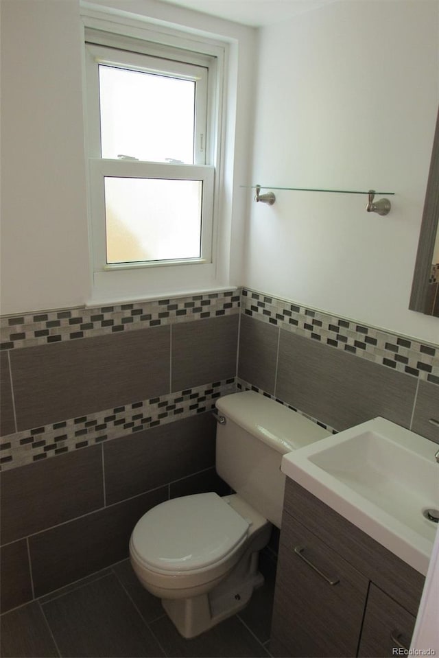 14503 E Wagon Trail Dr, Aurora, CO 80015 - bathroom with tile walls, vanity, toilet, and a wainscoted wall