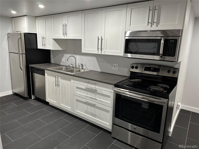 2201 Lima St, Aurora, CO 80010 - kitchen featuring a sink, white cabinetry, dark tile patterned flooring, dark countertops, and appliances with stainless steel finishes