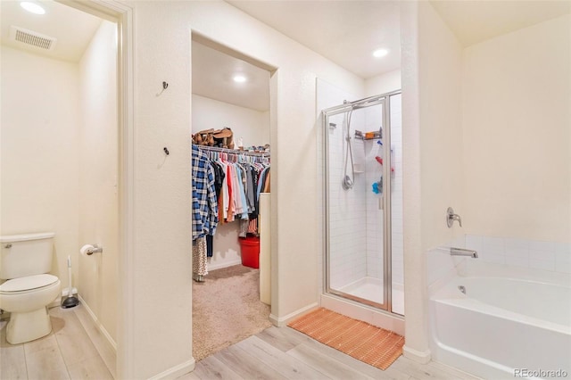 full bath featuring toilet, visible vents, a bath, a stall shower, and a walk in closet