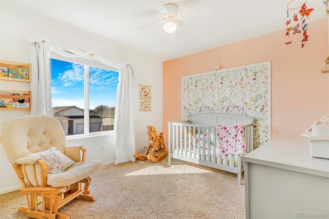 carpeted bedroom featuring a ceiling fan, a crib, and baseboards