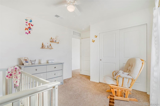 bedroom with light colored carpet, a ceiling fan, visible vents, a closet, and a nursery area