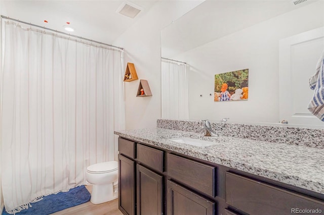 full bathroom featuring toilet, visible vents, wood finished floors, and vanity