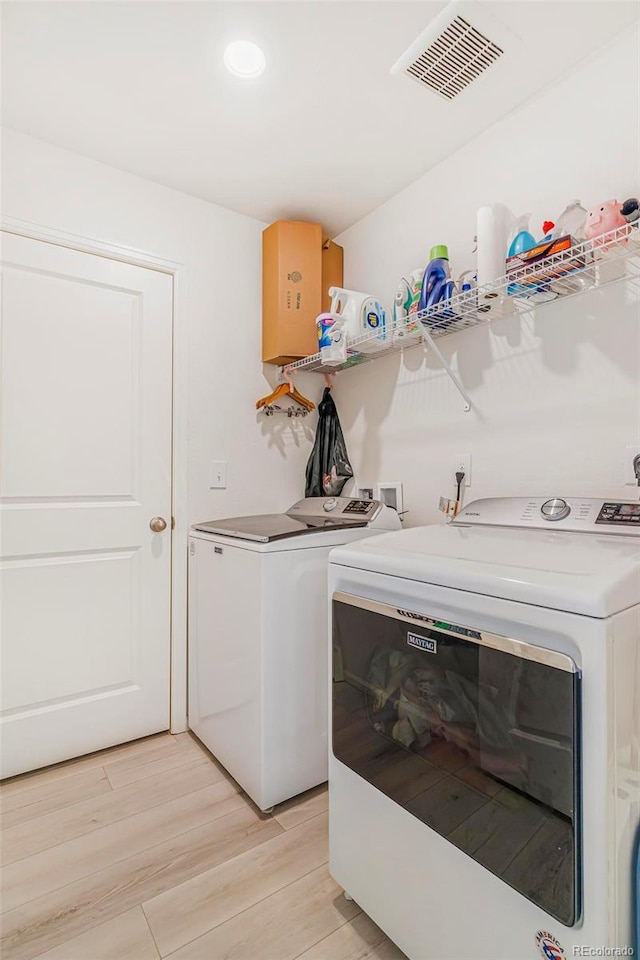 laundry area featuring laundry area, light wood-type flooring, washing machine and clothes dryer, and visible vents