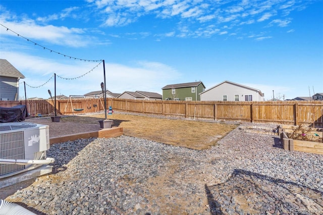 view of yard featuring central AC, a fenced backyard, and a garden