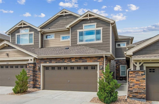 view of front facade with an attached garage, stone siding, a shingled roof, and concrete driveway