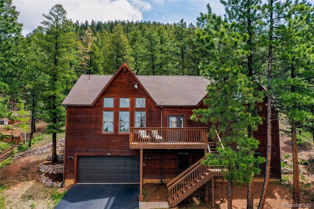 1321 Forest Edge Rd, Woodland Park, CO 80863 - rustic home with driveway, an attached garage, a wooded view, a wooden deck, and stairs