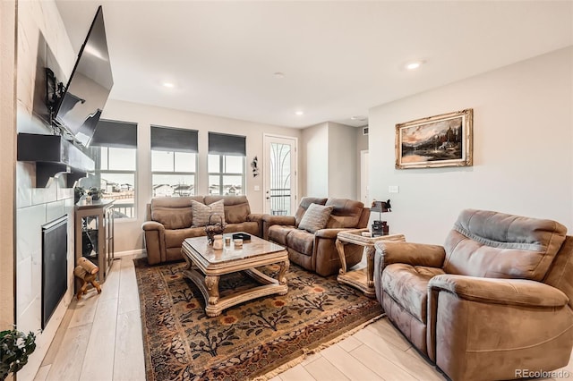 living room featuring a tile fireplace and light hardwood / wood-style flooring