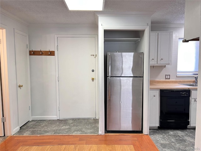 kitchen featuring sink, crown molding, a textured ceiling, black dishwasher, and stainless steel refrigerator