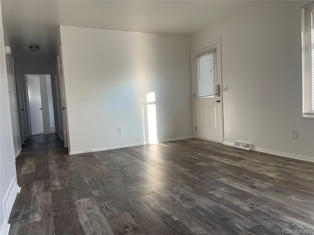 unfurnished room featuring baseboards, visible vents, and dark wood-type flooring