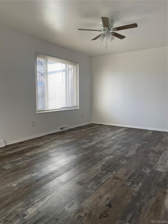 unfurnished room featuring a ceiling fan, dark wood finished floors, visible vents, and baseboards